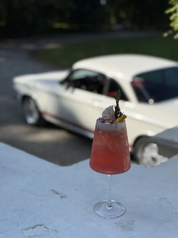 Rožinis kokteilis prie balto retro automobilio