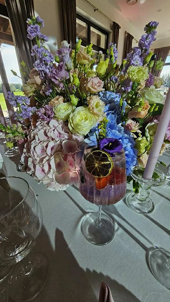 Violetinis kokteilis prie gėlių puokštės